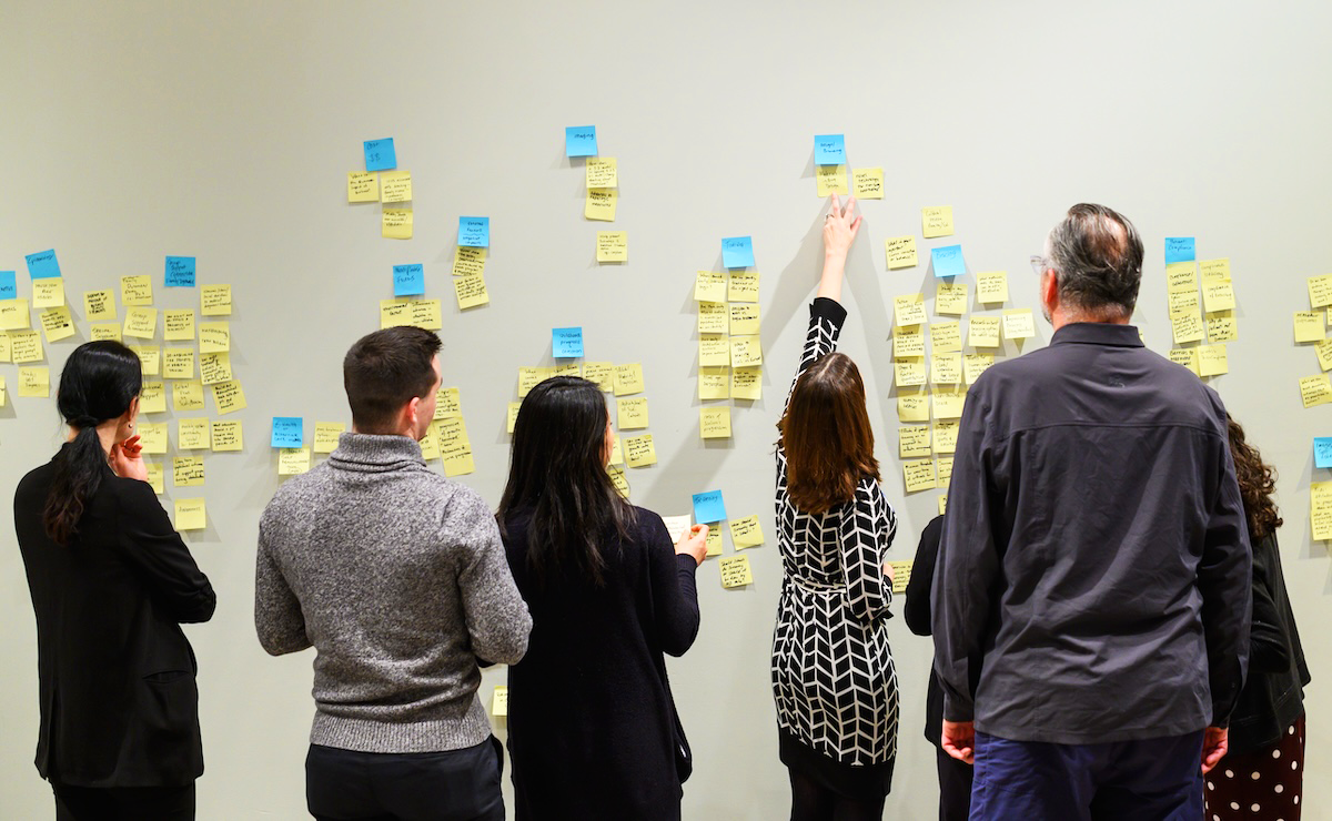 a group of people placing post-it notes on a wall